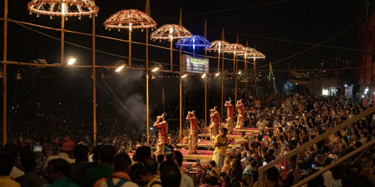 A diverse crowd gathered at night, attentively watching a live performance under bright stage lights.